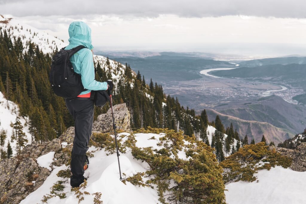 behind shot of a man standing on top of a carpathian mountain with a view of olt river in romania