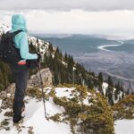 behind shot of a man standing on top of a carpathian mountain with a view of olt river in romania